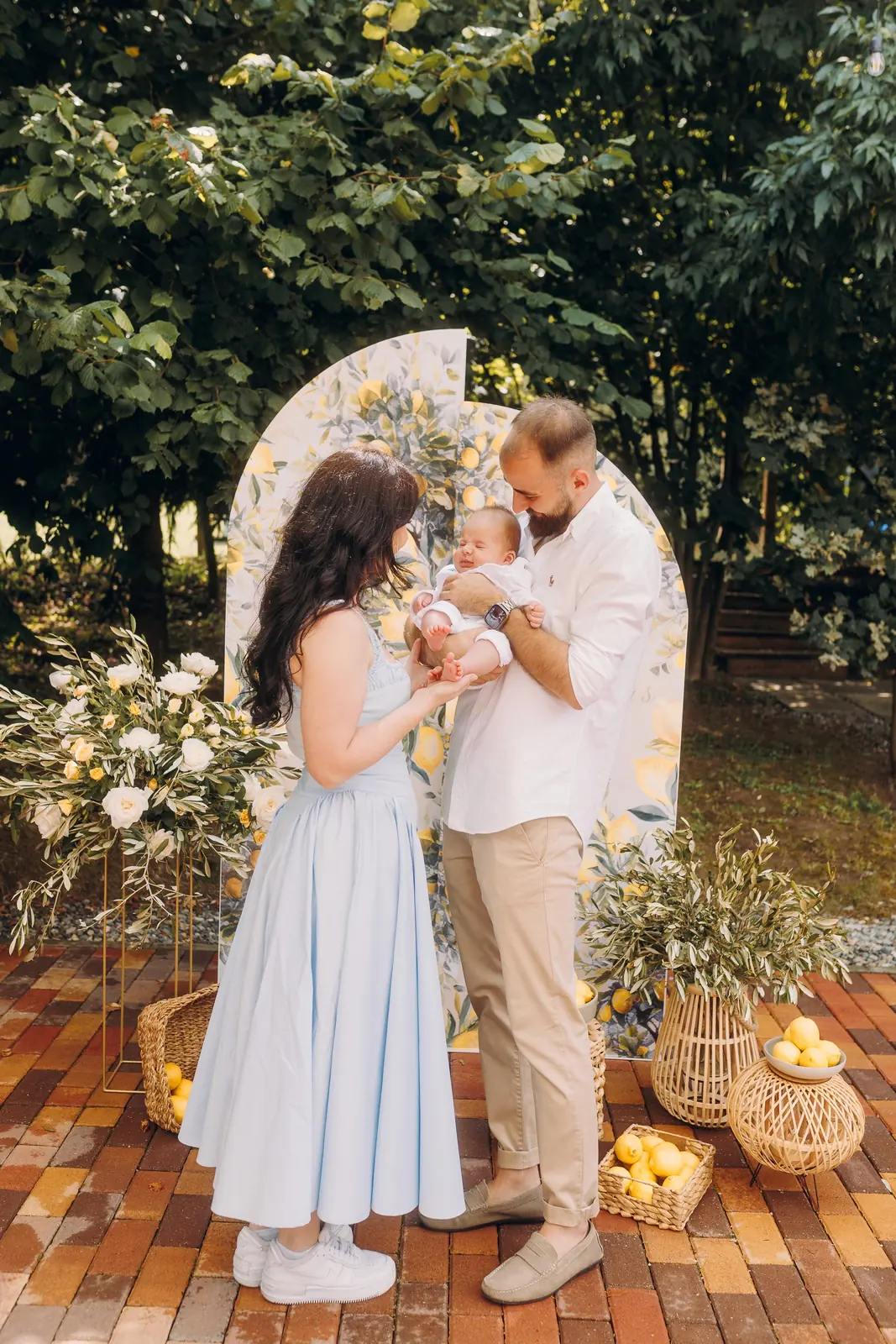 Decor de botez în grădină, cu panou pictat cu lămâi și aranjamente florale albe
